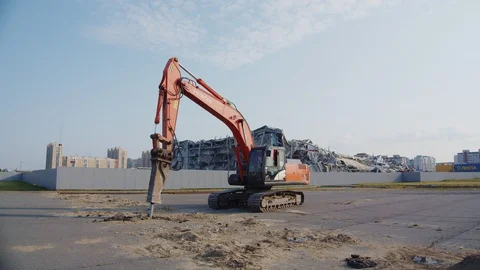 Machine digs pits under workers control near demolition site Stock Footage 127743882