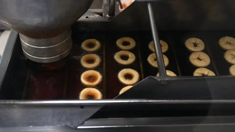 The machine forms and fries mini donuts in oil. Cooking mini donuts in Stock Footage 244683630