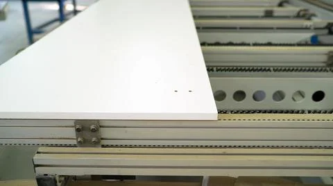 The machine makes a hole in the wood panel. A piece of wooden furniture rests Stock Photos