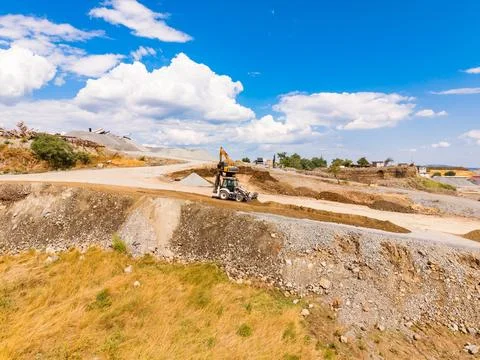 A machine operates in a granite quarry site during the day. The ground is cov Stock Photos
