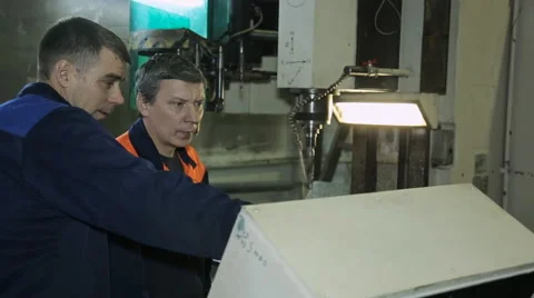 Machine operator shows a colleague a job and adjusts coolant Stock Footage 64560974