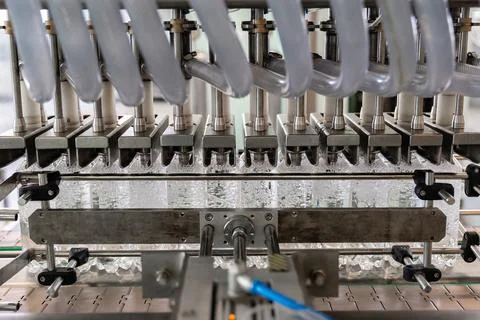 Machine pours water into plastic bottles. Closeup. Stock Photos