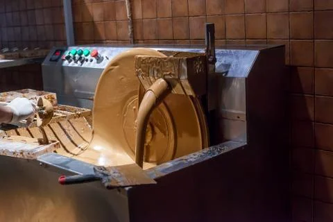Machine processes and creation chocolate. Pouring milk chocolate Foto stock