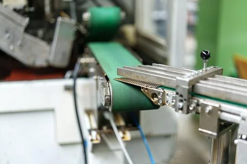 Machine processes material on a conveyor belt in a factory during working hou 스톡 사진