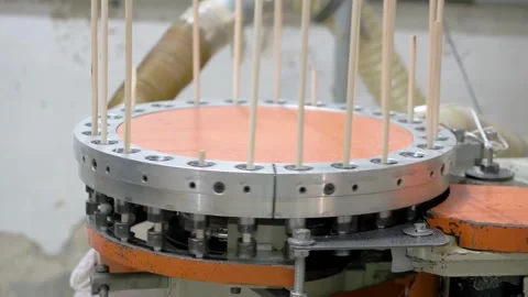 A machine processes wooden dowels, arranging them vertically in a rotating Stock Footage 307690929