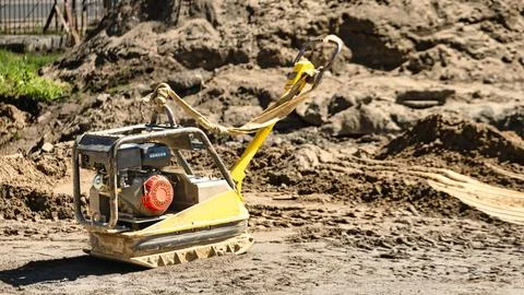 A machine is processing soil on a construction site. The area is busy with .. Stock Photos