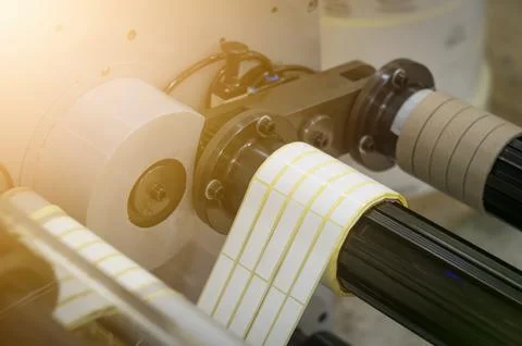 A machine for the production of white self-adhesive labels. The shafts of the Stock Photos