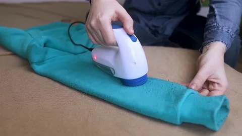 Machine for removing pellets. The girl uses a special device to remove lint from Stock Footage 228963519