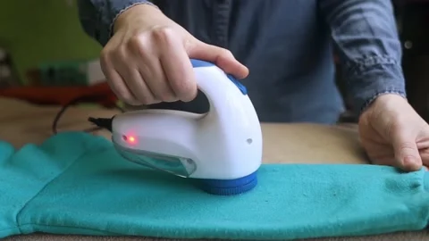 Machine for removing pellets. The girl uses a special device to remove lint from Stock Footage 228964546