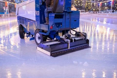 A machine for restoring or smoothing ice rides on an ice rink in the evening.	 Stock Photos