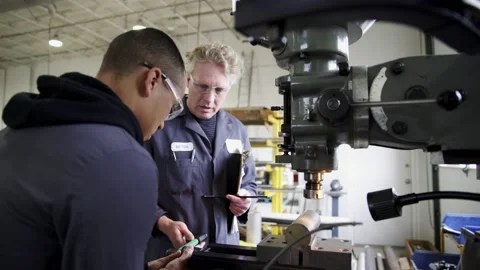 Machine shop worker training apprentice using milling machine Video stock 220353714