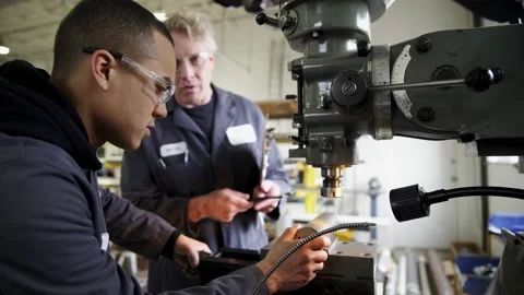 Machine shop worker training apprentice using milling machine Stock Footage 220353763
