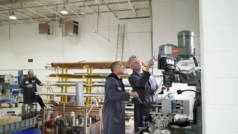 Machine shop worker training apprentice using milling machine Stock Footage 220353832