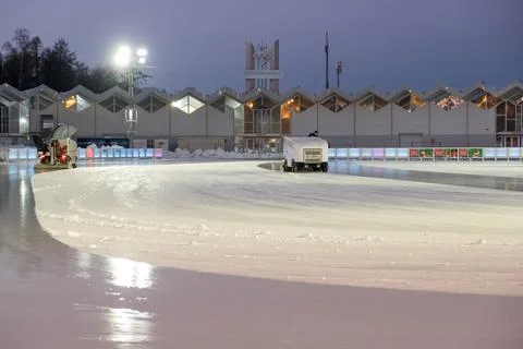 Machine smoothly resurfaces ice at a skating rink in the evening light during Stock Photos