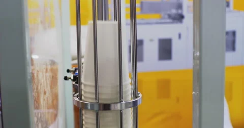 Machine stacking disposable cups on yellow background Stock Footage 313061627