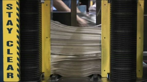 A machine stacks and binds newspapers in a factory. Stock Footage 556355