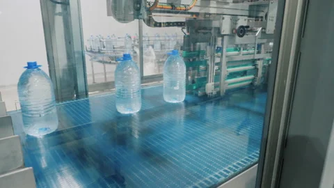 Machine tool arm moves bottles with water on conveyor Stock Footage 160853209