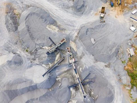 Machinery processes granite at a quarry. Large piles of stone are arranged ar Stock Photos