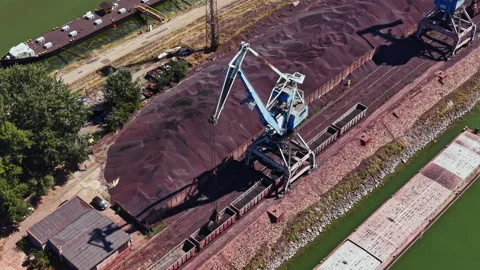 Machines load cargo on a barge at a dock near a waterway in the afternoon sun Stock Footage 344233566