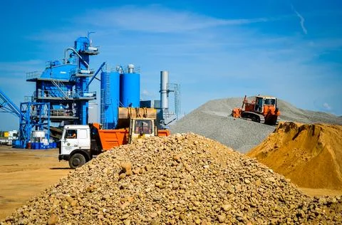 Machines work on loading and unloading material for the production of asphalt Stock Photos