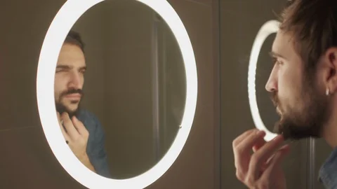 Macho man fixing beard in front of the bathroom mirror Stock Footage 127648903