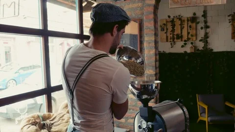 Macho man pouring coffee beans in the roasting machine Stock Footage 95911960
