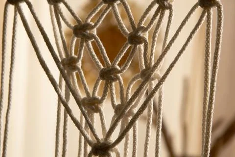 Macrame lace pattern of threads tied into knots. Light cotton ropes woven with a Stock Photos