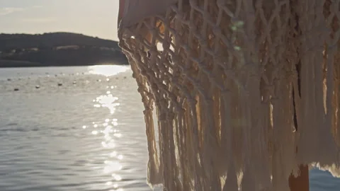 Macrame Net Pattern Backlit by Golden Sunset Light Over Calm Bay 4K Cinematic Stock Footage 338403022