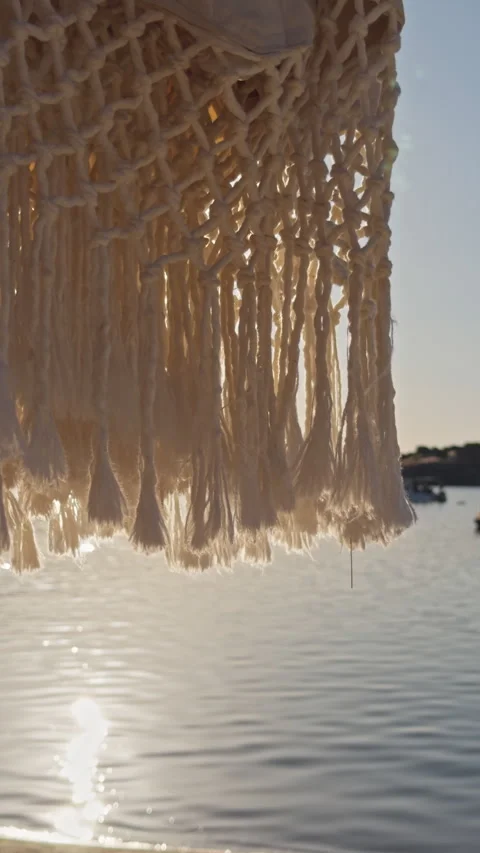 Macrame Net Pattern Backlit by Golden Sunset Light Over Calm Bay 4K Cinematic Stock Footage 338403242