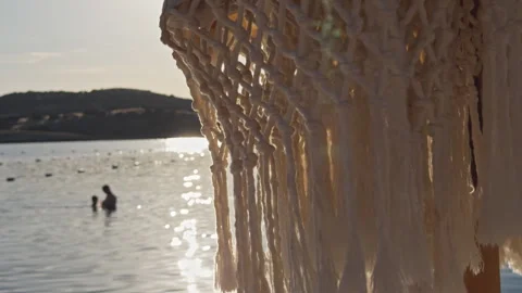 Macrame Net Pattern Backlit by Golden Sunset Light Over Calm Bay 4K Cinematic Stock Footage 338403329