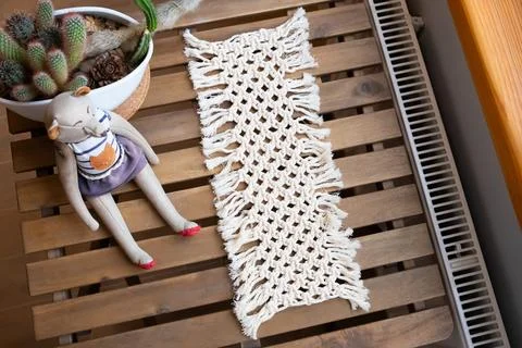 Macrame table runner made of cotton thread on wooden table. Decorative Stock Photos