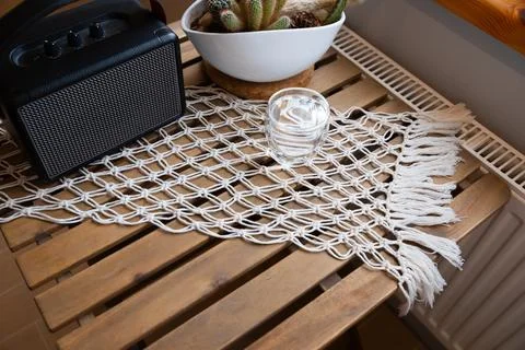 Macrame table runner on wooden table with speaker and cactus. Bohemian styl.. Stock Photos