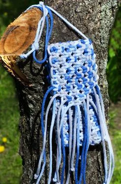 Macrame technique bag for mobile phone on green grass background. Foto stock