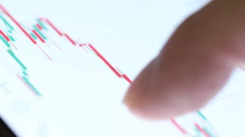 Macro 4K footage of a finger tapping a green and red candlestick graph on a mobi 스톡 동영상 342777998