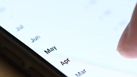 Macro 4K view of a finger scrolling through a vertical list of abbreviated month Stock Footage 342777996