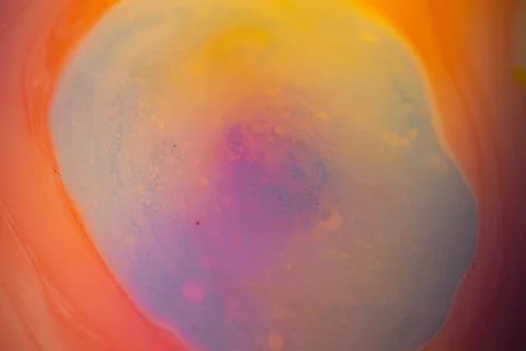 Macro abstract image of pastel liquid paint forming a soft swirling pool. Stock Photos