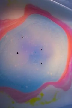 Macro abstract image of a soft blue liquid puddle surrounded by pink. 写真素材