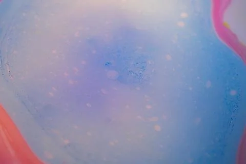 Macro abstract image of a soft blue liquid puddle surrounded by pink. 写真素材