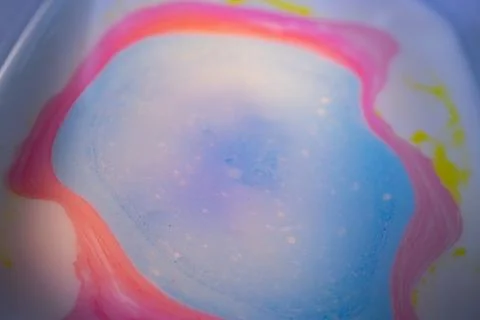 Macro abstract image of a soft blue liquid puddle surrounded by pink. 写真素材