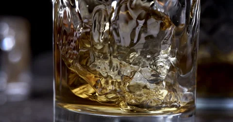 Macro of aged bourbon whiskey poured in transparent glass with ice cubes Video stock 269382640