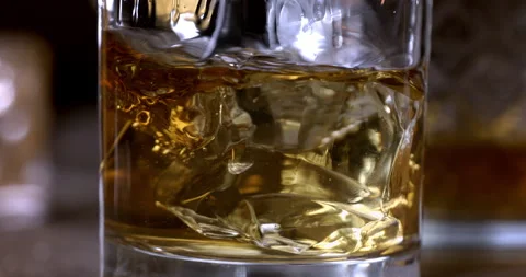 Macro of aged bourbon whiskey poured in transparent glass with ice cubes Video stock 269382657