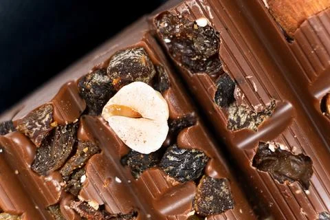 Macro background of milk nut chocolate with raisins. Stock Photos