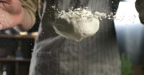 Macro of baker sprinkles flour on raw loaf of dough while making bread or pizza Stock Footage 268835578