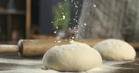 Macro of baker sprinkles flour on raw loaf of dough while making bread or pizza Stock Footage 268838879