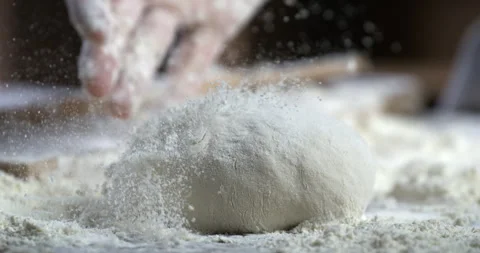 Macro of baker sprinkles flour on raw loaf of dough while making bread or pizza Video stock 269328121