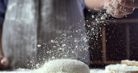 Macro of baker sprinkles flour on raw loaf of dough while making bread or pizza Stock Footage 269330788