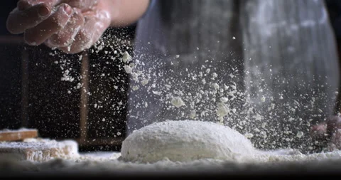 Macro of baker sprinkles flour on raw loaf of dough while making bread or pizza Video stock 269331554