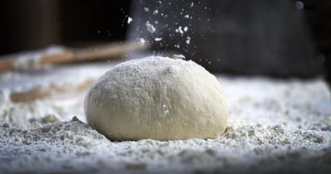 Macro of baker sprinkles flour on raw loaf of dough while making bread or pizza Video stock 269332075