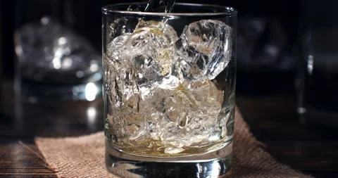 Macro of bourbon whiskey poured in transparent glass with fresh cool ice Stock Footage 270045725