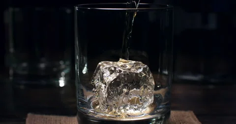 Macro of bourbon whiskey poured in transparent glass with fresh cool ice Stock Footage 270046089